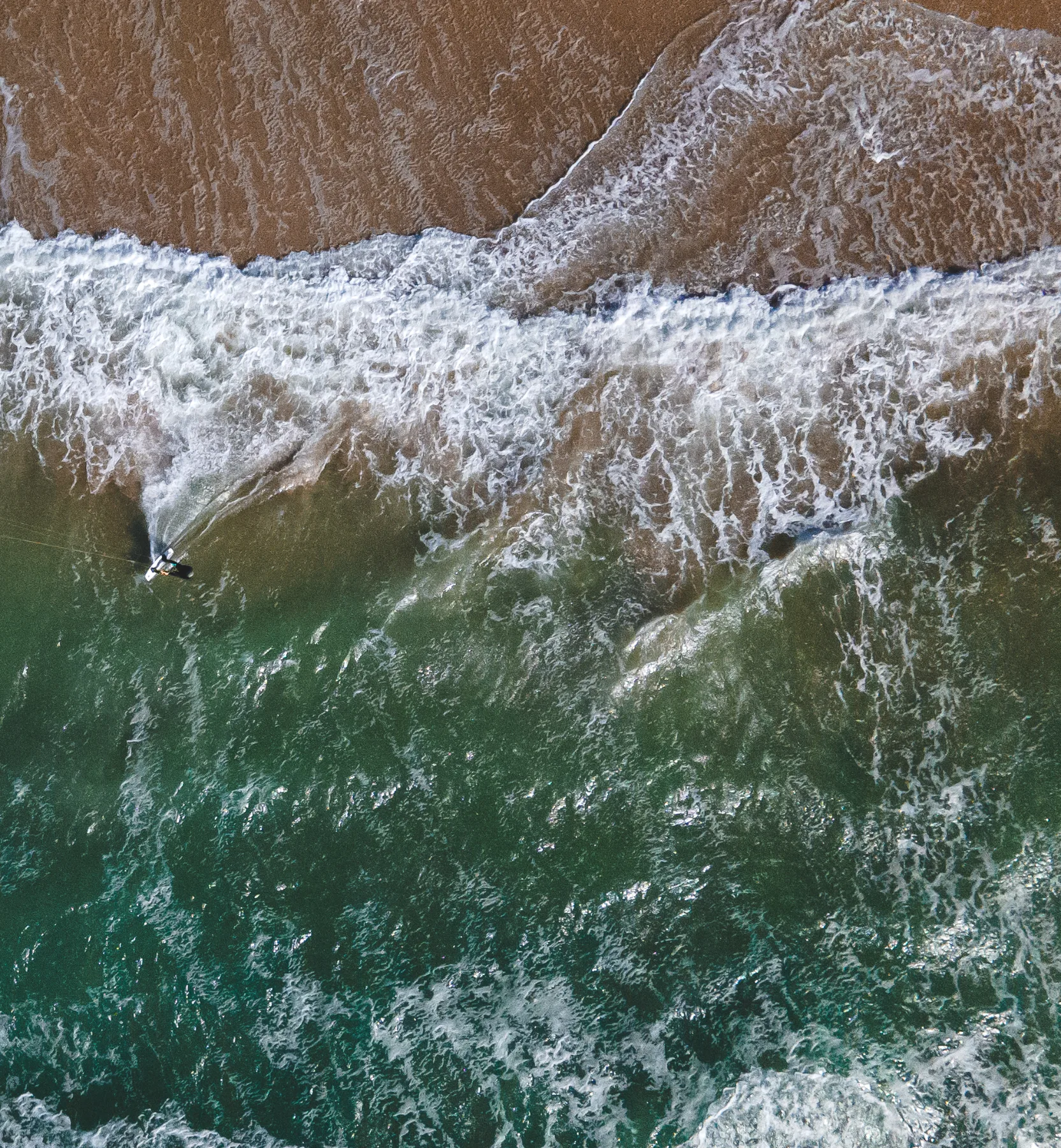 Big teal Ocean waves on beach from birds-eye view.
